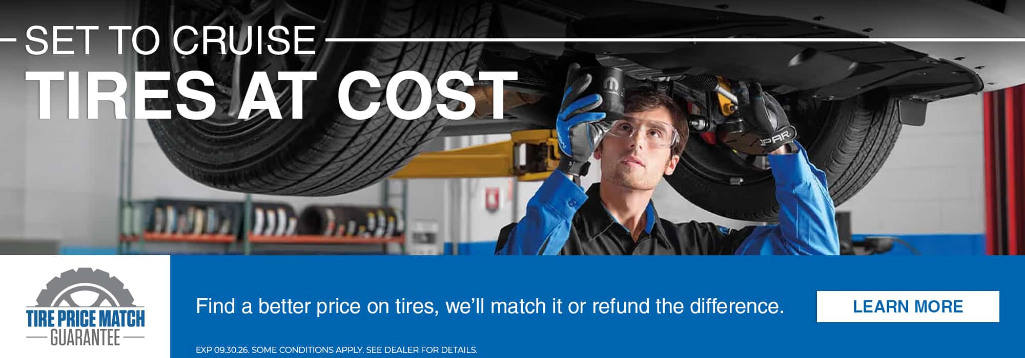 Mechanic working on a car with "Tires at Cost" offer; includes a tire price match guarantee.