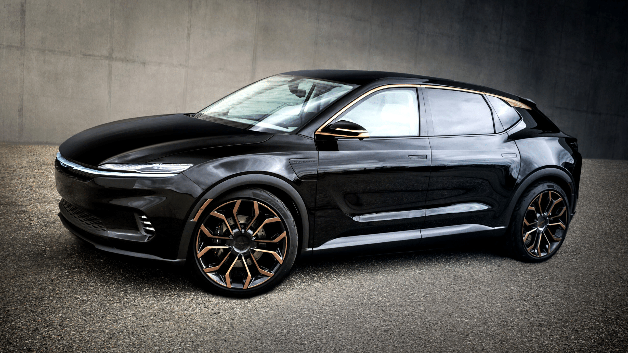 Sleek black luxury SUV with gold-accented wheels, parked in a modern, minimalist concrete setting.