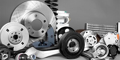 Assorted car parts including brake discs, springs, and pulleys on a gray background.