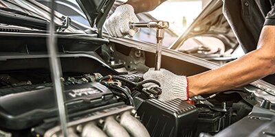 Mechanic using a ratchet wrench to repair a car engine, emphasizing auto maintenance.