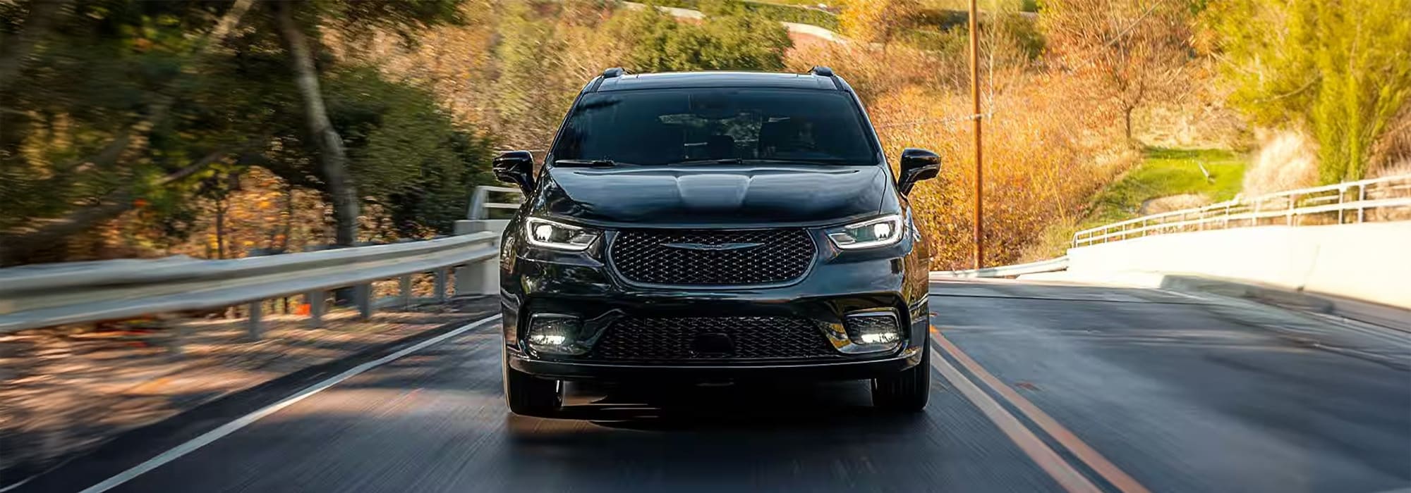 Black GMC pickup truck parked on a sandy beach, with rocky cliffs in the background.