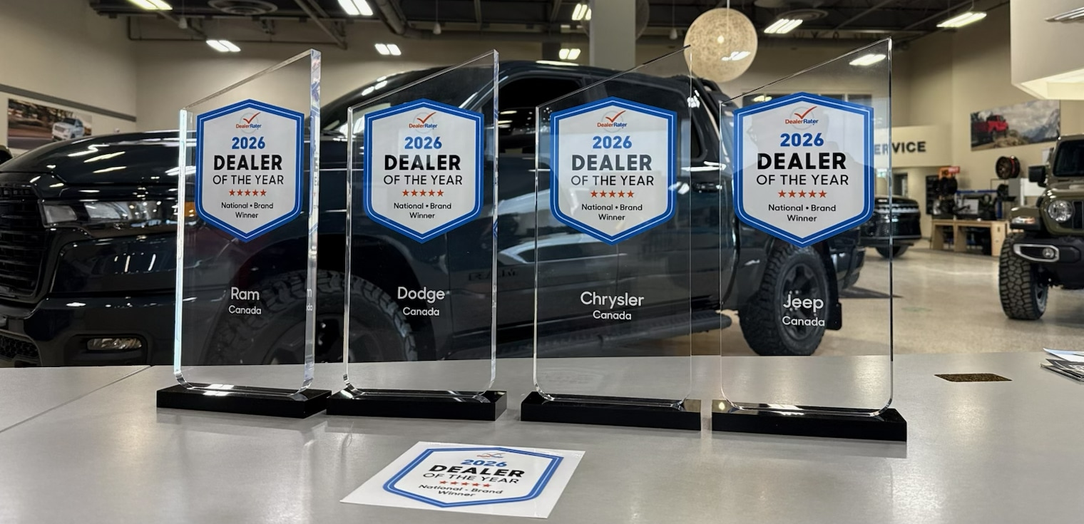 Black GMC pickup truck parked on a sandy beach, with rocky cliffs in the background.