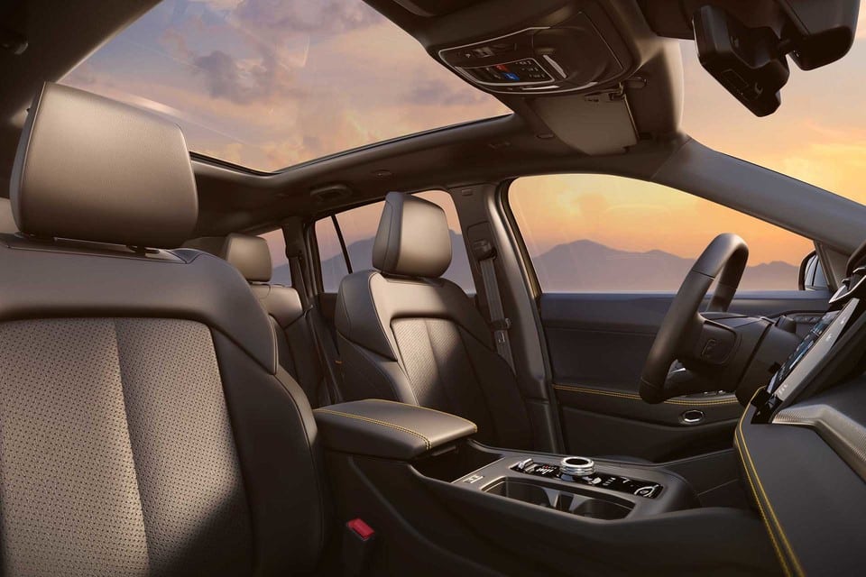 Luxurious car interior with leather seats and panoramic sunroof, sunset view outside.