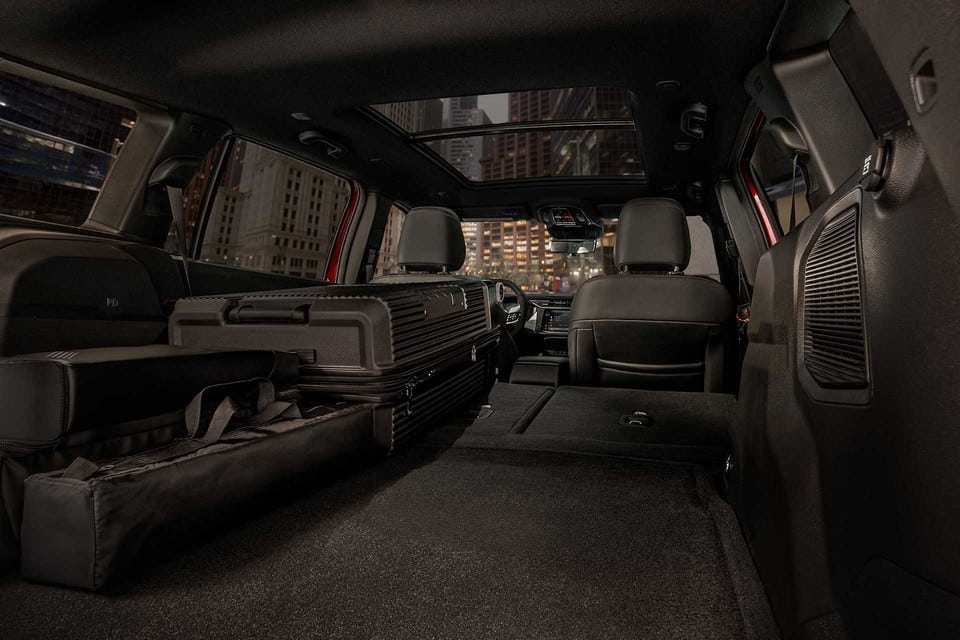Spacious car interior with folded seats and luggage, showcasing storage capacity at night.